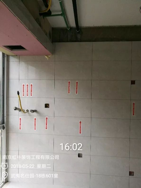 南京武夷名仕園124平米簡美風格裝修  享受家?guī)淼臏囟?0五月份_墻磚鋪貼完成后，紅牛裝飾的工人會用專用護角條對瓷磚角保護，用標貼標出水管、線管走向示意。